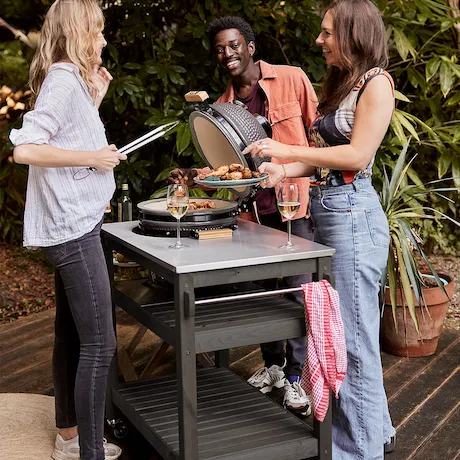 Grilltisch im Garten mit Personen, die zusammen grillen und Spaß haben